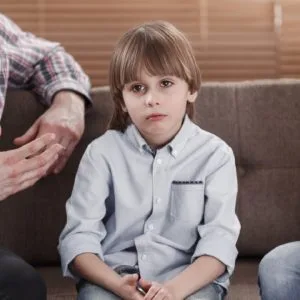 Sad young boy sitting on a couch between his parents as they talk